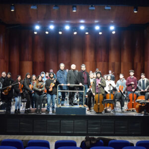 Orquesta de jóvenes de la Pintana, al centro, de derecha a izquierda, Fernando Saavedra (Director de la orquesta), Pascal Gallois (Director del Conservatorio Mozart de París), Diego Pérez de Arce (Presidente de Apertio).